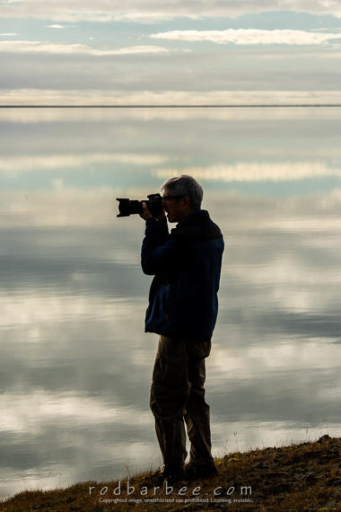 Photographer in the sky. Reflection in still water.